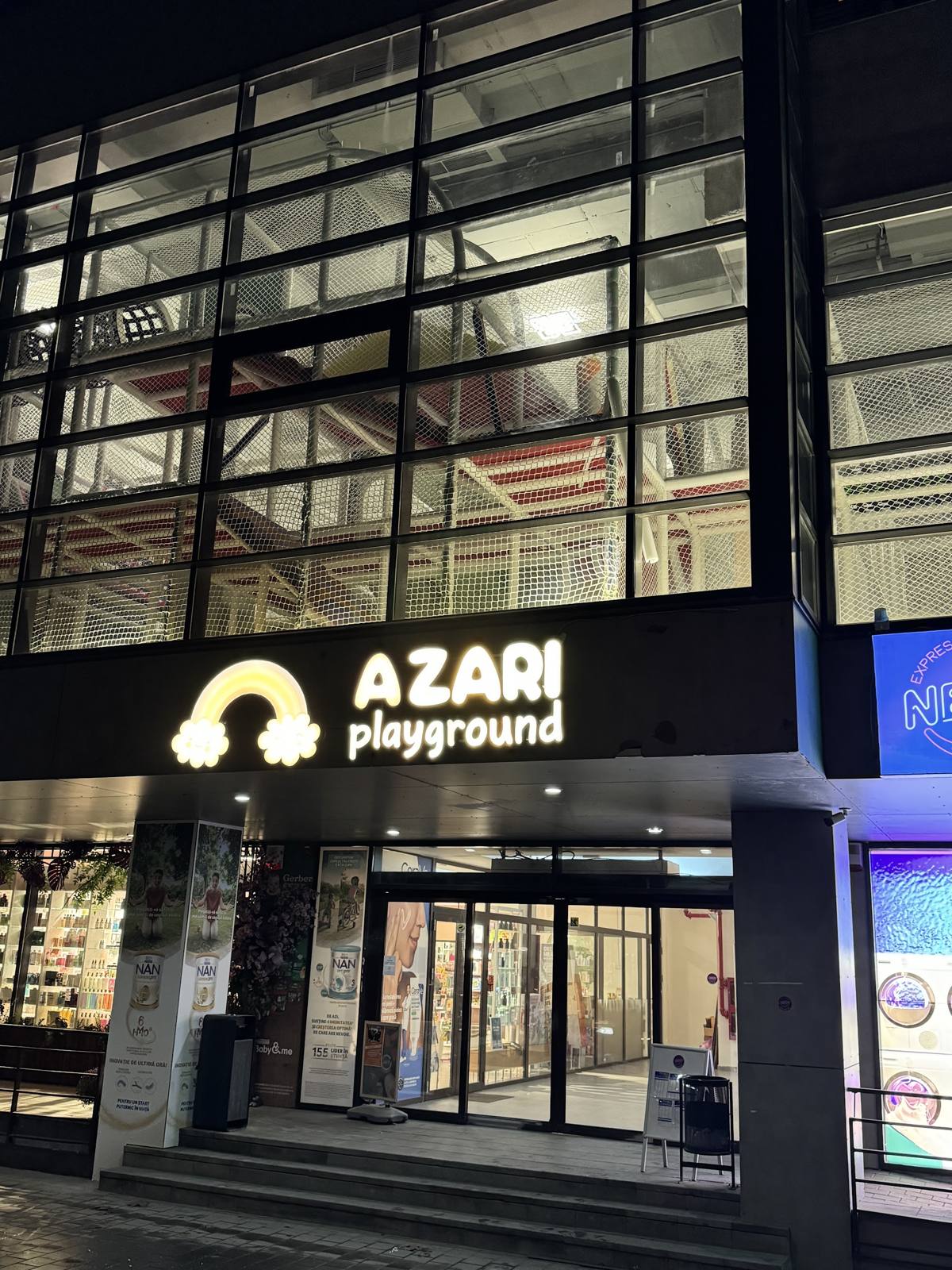 Intrarea Azari playground seara, cu sigla curcubeu luminoasă