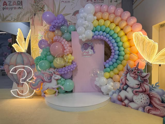 Arcadă de baloane în culorile curcubeului, cu unicorn și cifra 3 luminoasă